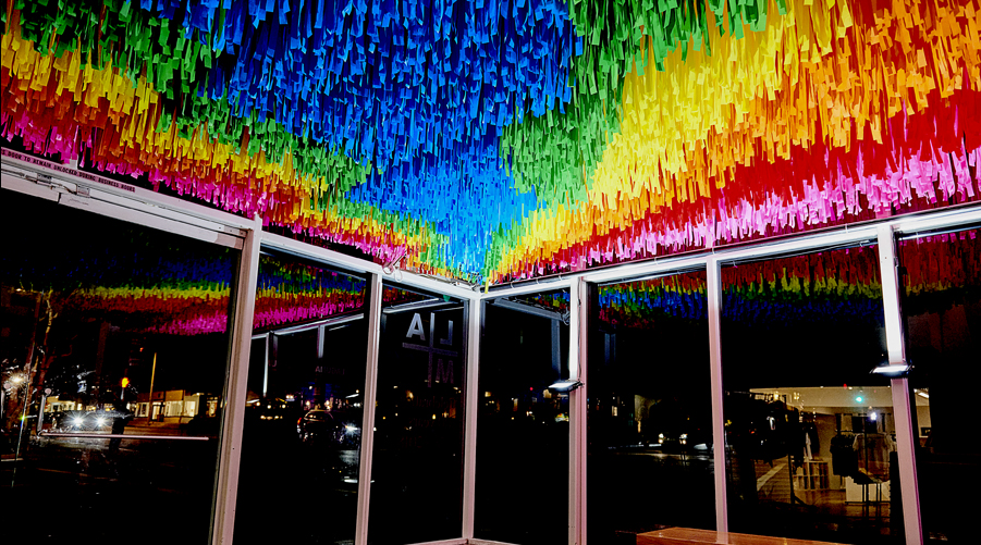 A rainbow-hued, large-scale installation at the Laguna Art Museum in Laguna Beach, California that is suspended from the ceiling, comprised of colorful flagging tape.
