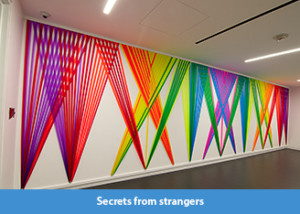 A rainbow hued wall weaving of plastic flagging tape on view at the Wells Fargo Center in Los Angeles, CA