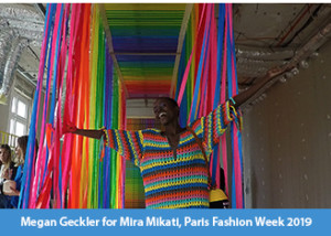 A photograph of a model at the end of an upside down rainbow catwalk designed by Megan Geckler, clothes by Mira Mikati for Paris Fashion Week 2019
